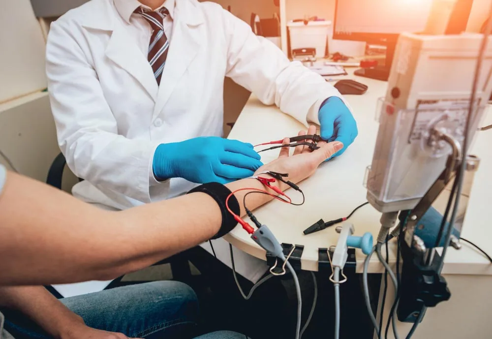 Dr. Helder Ribeiro realizando um exame de eletroneuromiografia no braço de uma paciente